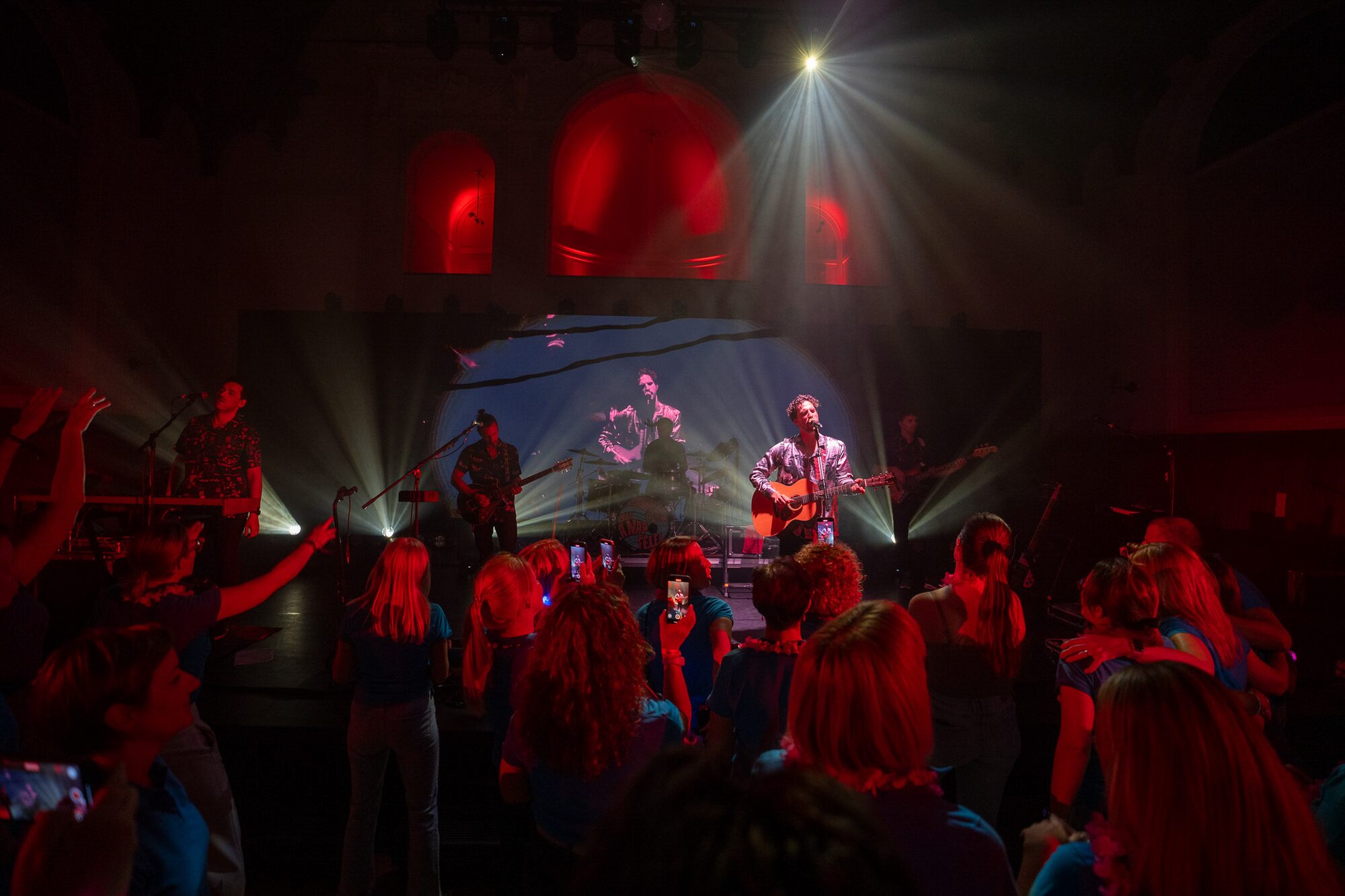 Élő zenés koncert piros fényekkel, táncoló vendégekkel
