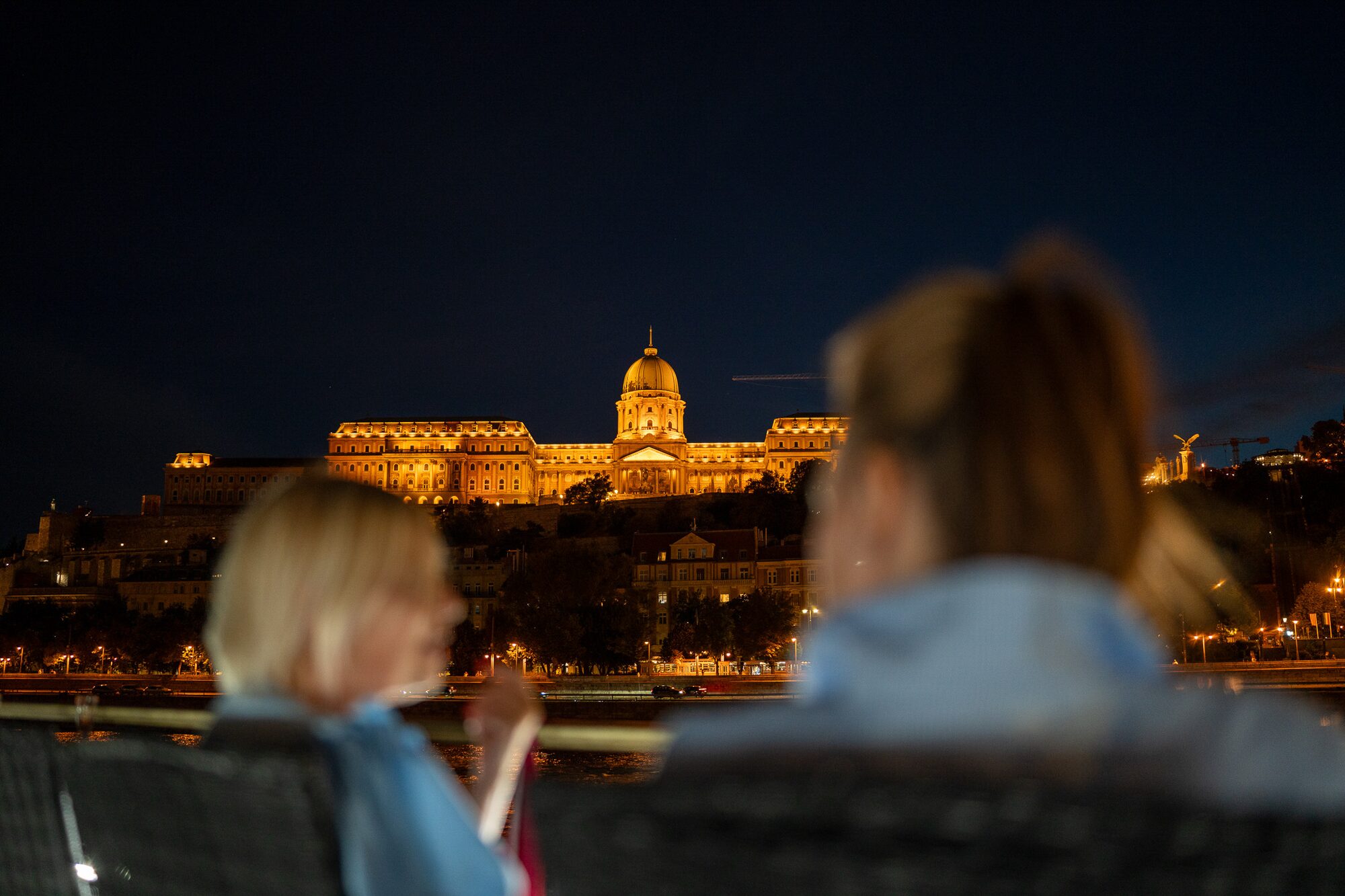 Esti program a Duna mentén, háttérben a kivilágított Budavári Palotával