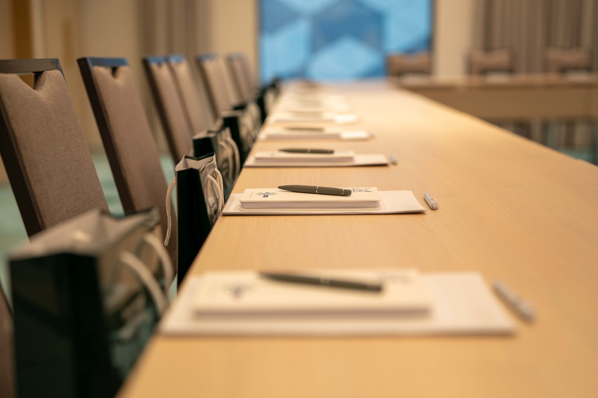Conference table laid with notebooks, pens and gift bags